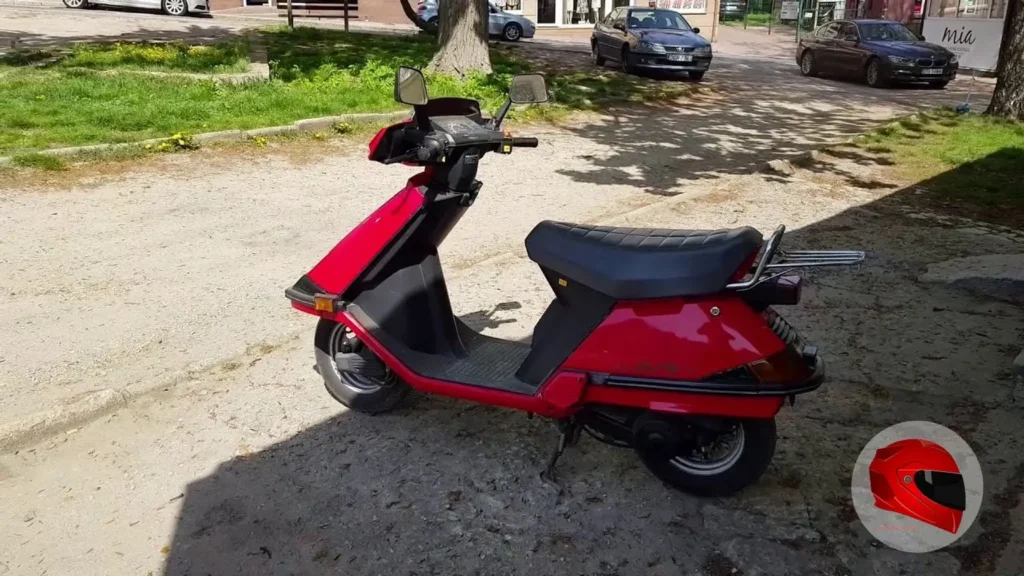 Red Honda Elite 80 in full side profile parked outdoors