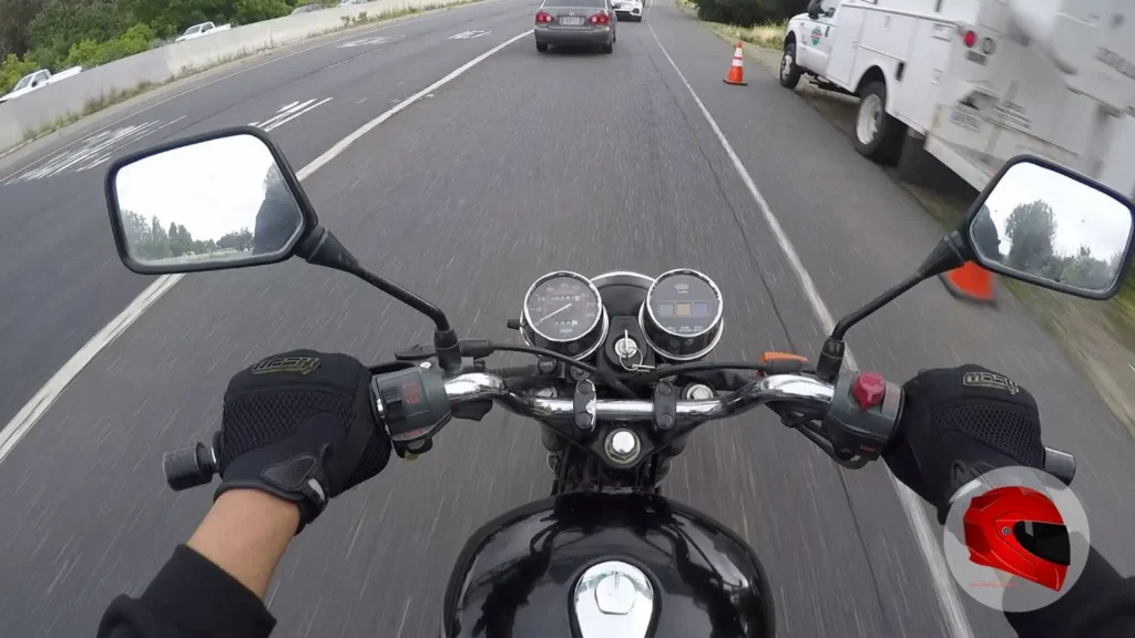 Rider's view from a Honda Nighthawk 250 on a highway commute, showing the handlebars and twin dials